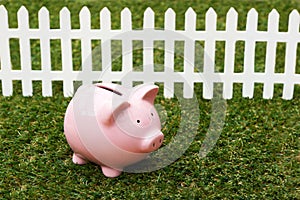Piggy Bank On Grass With White Fence