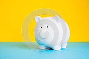 Piggy bank isolated on yellow and blue background copy space. Money saving concept.