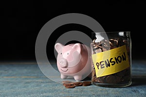 Piggy bank and jar of coins with word PENSION on table.