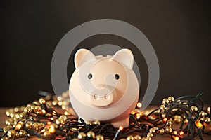 Piggy bank on a light Christmas string. Concepts: savings on holiday shopping