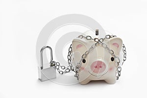 Piggy bank is locked by chain and key on white background, saving