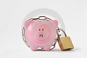 Piggy bank locked with chain and padlock on white background - Concept of savings and financial protection