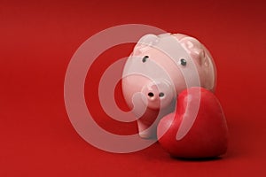 Piggy bank in love with red heart on red background