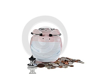 Piggy bank with medical mask and stethoscope plus coins for financial crisis concept