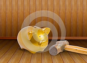 Piggy bank and old hammer on wood background.