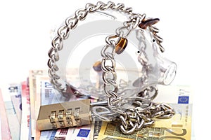 Piggy bank padlocked with chains and padlock on euro banknotes
