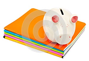 Piggy bank on pile of copybooks