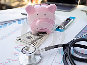 piggy bank on pile of dollar, graph and calculator. coins stack. stethoscope