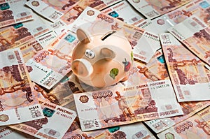 Piggy bank in a pile of russian five thousand banknotes