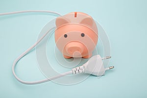 Piggy bank with power plug on blue background