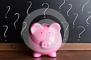 Piggy bank with question mark on black board