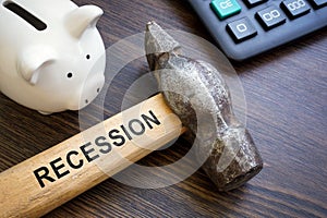 Piggy bank for savings and hammer with word recession.