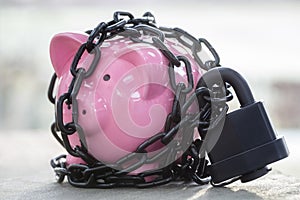Piggy bank secured with padlock chained up and locked