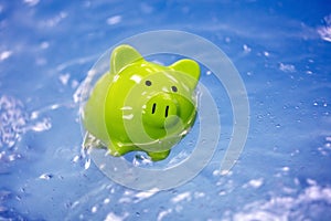 Piggy bank sinking in water drowning in debt