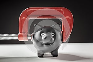 Piggy bank squeezed with red clamp financial problems photo