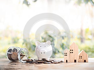 Piggy bank on stack of coins and miniature house. The saving concept for house and property