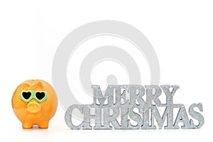 A piggy bank standing next to a Merry Christmas sign.