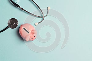 Piggy bank with stethoscope on blue background. Top view with copy space