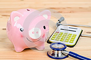 Piggy bank and stethoscope with calculator.