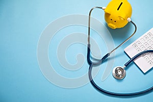 Piggy bank with stethoscope and calculator on the blue background