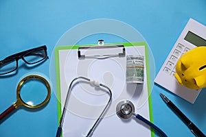 Piggy bank with stethoscope and calculator on the blue background