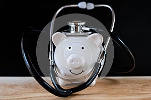 Piggy bank with stethoscope, check health savings regularly concept