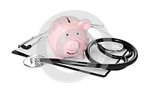 Piggy bank, stethoscope and clipboard on white