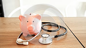 Piggy Bank, Stethoscope  and dollars on wooden table in  White Background