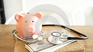Piggy Bank, Stethoscope  and dollars on wooden table in  White Background