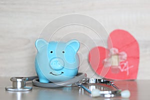 Piggy bank with stethoscope and red heart on wooden background,Save money for Medical insurance and Health care concept