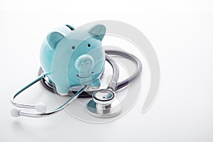 Piggy bank with stethoscope on white background