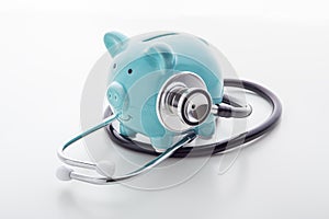 Piggy bank with stethoscope on white table