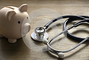 Piggy bank and a stethoscope on a wooden background