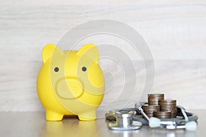 Piggy bank and stethoscope on wooden background, Save money for Medical insurance and Health care concept