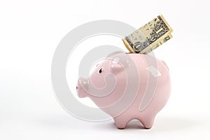 Piggy bank style money box with one dollar falling into slot on a white studio background