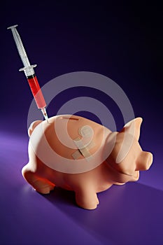 Piggy bank with syringe, financial metaphor