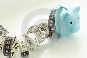 Piggy bank with tape measure on white background