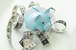 Piggy bank with tape measure on white background