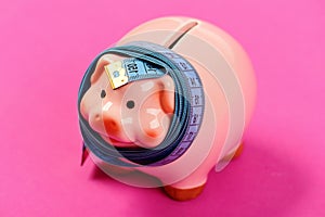 Piggy bank tied with measuring tape showing number 150