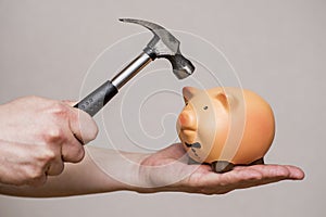 Piggy bank is about to be hit by a hammer. Male hand with a hammer and a piggy bank. Man with hammer about to smash piggy bank to