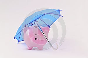 Piggy bank under blue umbrella - Concept of money protection and financial security