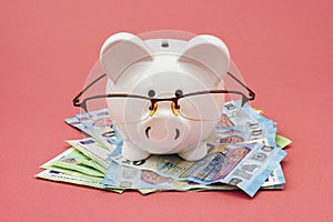 Piggy bank wear glasses standing on a pile of cash