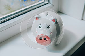 Piggy bank at window sill indoors, closeup. Space for text