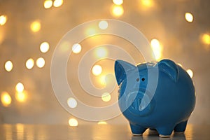 Piggy bank on wooden table against blurred Christmas lights