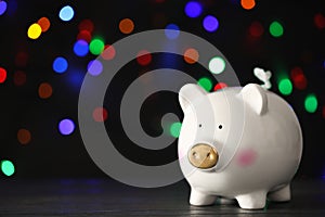 Piggy bank on wooden table against blurred Christmas lights