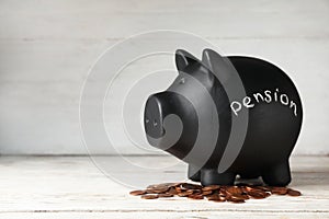 Piggy bank with word PENSION and coins on table