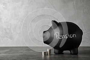 Piggy bank with word PENSION and coins on table