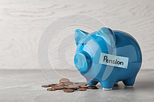 Piggy bank with word PENSION and coins on table