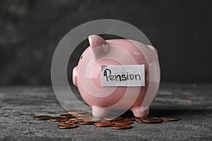 Piggy bank with word PENSION and coins on table