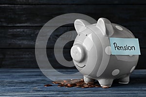 Piggy bank with word PENSION and coins on table